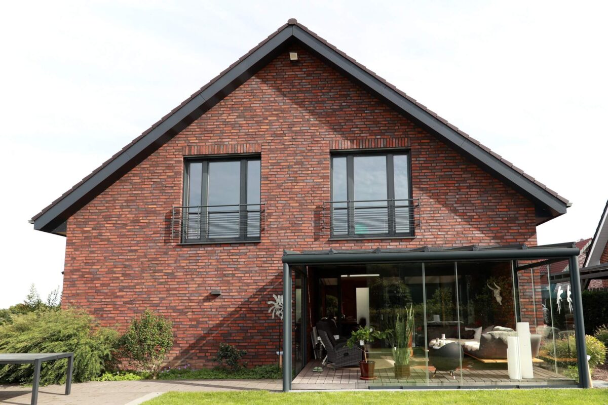 Außenansicht eines Einfamilienhauses. Im Vordergrund ist eine moderne, verglaste Terrasse zu sehen. Das Objekt ist eine Referenz des Thoma Partners Zimmerer Profibau. - Zimmerer-Profibau GmbH - Thoma Holz100 