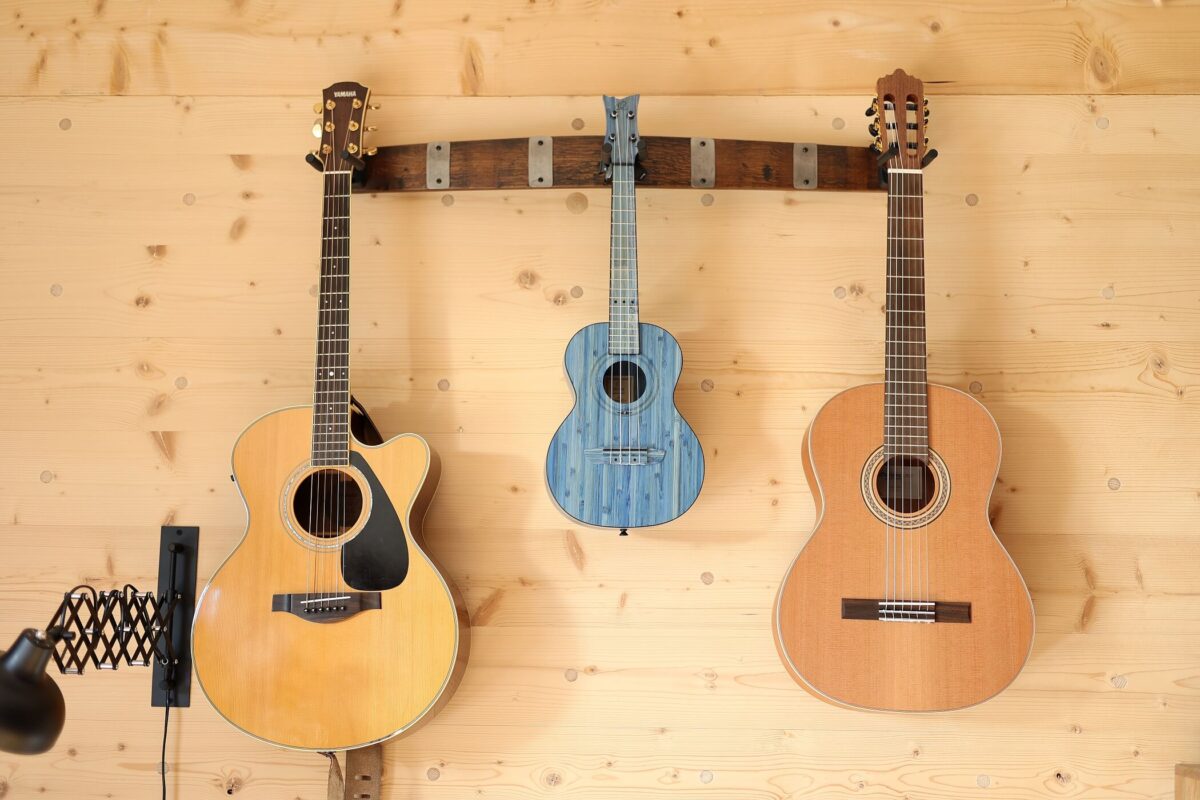 Detailbild von drei hängenden Gitarren vor einer Massivholzwand. Das Bild ist eine Referenz des Thoma Partners Zimmerer Profibau. - Zimmerer-Profibau GmbH - Thoma Holz100 