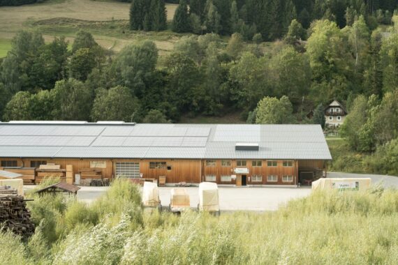 Das Bild zeigt das Thoma Holz100 Werk in Stadl aus der Luft, im Hintergrund sind grüne Bäume und Wiesen zu sehen. Das Bild ist Teil einer Stellenanzeige für Zimmerer & Tischler Fachkräfte (m/w/d) in Stadl-Predlitz. - Interesse an einem Job bei uns ? - Thoma Holz100